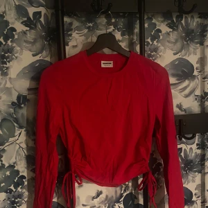 Röd långärmad topp från Noisy May - Säljer en snygg röd långärmad topp från Noisy May. Den har en cool knytdetalj i midjan som ger en unik look. Perfekt för både vardag och fest! 💃