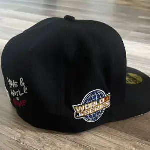 Snygg svart keps från New Era med broderad World Series-logga på sidan och ett coolt 'Love & Hate' motiv. Framsidan har ett stilrent vitt 'Sox' emblem och ett litet hjärta. Perfekt för sportfantaster eller som en stilren accessoar.