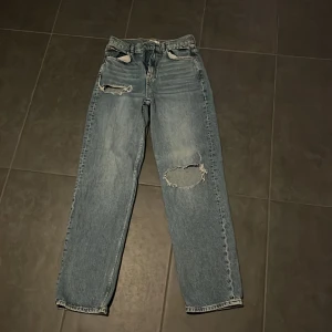 Blå jeans med slitningar från Perfect Jeans - Säljer ett par blå jeans från Perfect Jeans i storlek 34. De har coola slitningar på låret och knäet för en trendig look. Perfekta för en avslappnad stil och passar till både vardag och fest. 🕶️