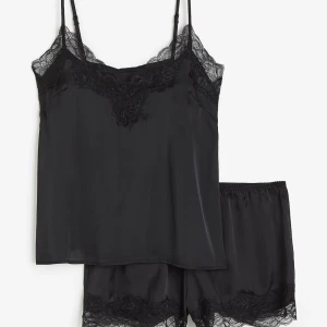 Svart satinlinne med spetsdetaljer - Snyggt svart satinlinne med tunna axelband och  spetsdetalj.  Matchande shorts med spetskant. Knappt använda, slutsålda i de flesta storlekar! Nypris 249. 