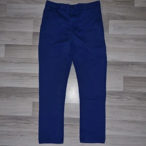 Blå chinos - Säljer ett par snygga blå chinos i bra skick. De har en klassisk design med knapp och dragkedja framtill samt en bakficka med knapp. 