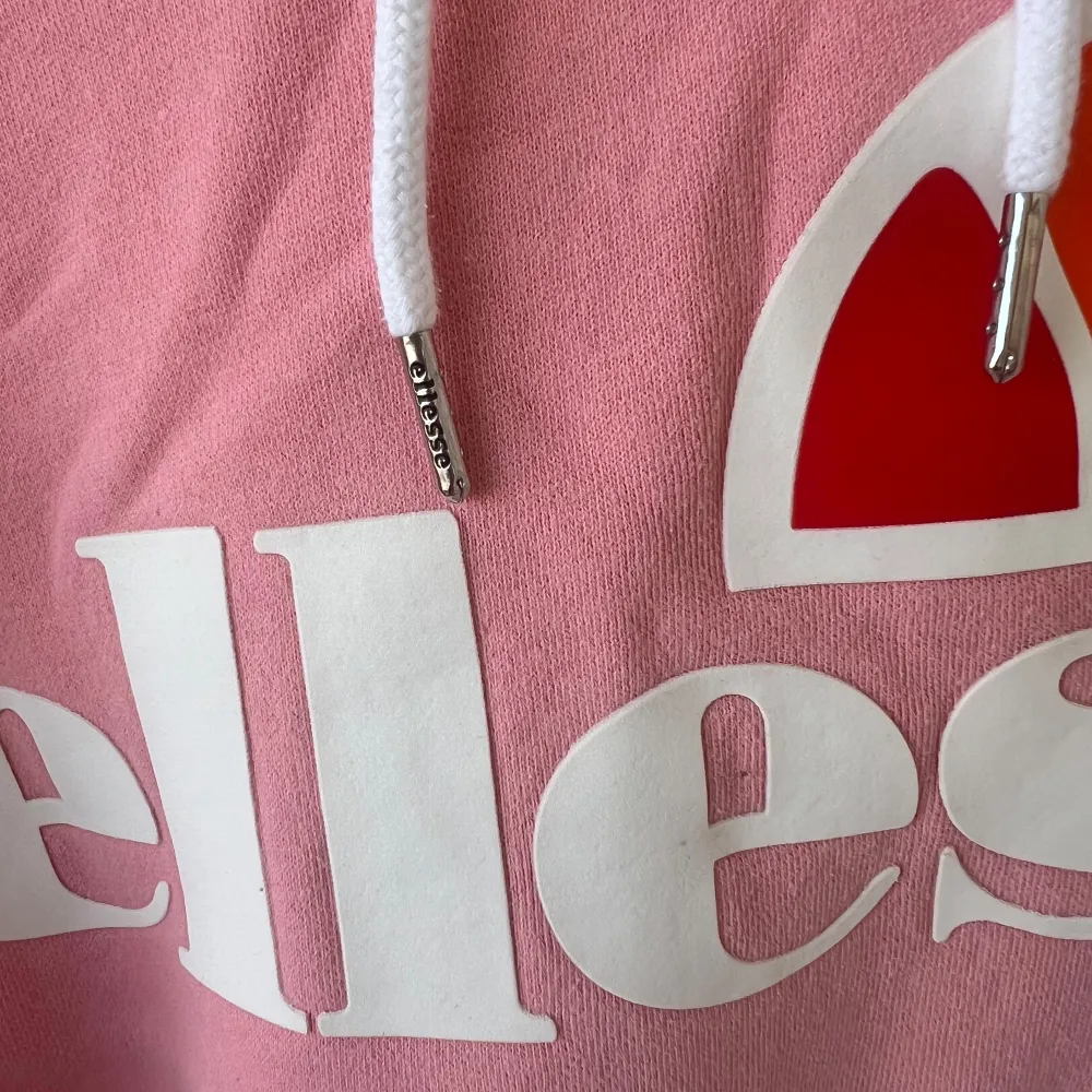 Säljer en superfin rosa hoodie från Ellesse i bra skick. Den har en stor logga på framsidan och en mysig huva med vita snören. Perfekt för chilliga dagar eller när du vill ha en sportig look. Stor ficka fram för att värma händerna eller förvara småsaker.. Tröjor & Koftor.