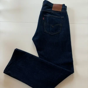 Levi's 501 Jeans - Säljer ett par klassiska Levi's 501 jeans i mörkblå denim. De har en rak passform och är i mycket bra skick. Hör av dig vid intresse!