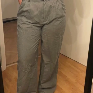 Grå kostymbyxor - Säljer ett par stiliga grå kostymbyxor i bra skick. De är högmidjade med en rak passform. Perfekta för både kontoret och mer formella tillfällen. Säljer då dem tyvärr är för stora, har tappat en hylsa men funkar jättebra med en och knappen som man stänger med :)