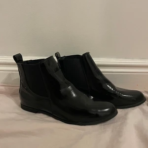 Svarta lackskor - Säljer svarta lack imitation skor. Jag har fått dom så vet inte hur använda dom men är i mycket fint skick. Fina detaljer. Storlek 39. Köparen betalar frakten. 