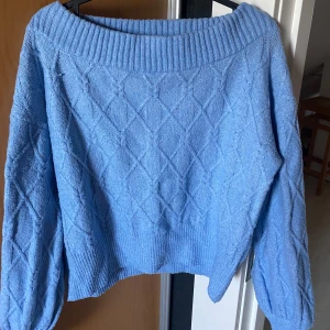 Blå stickad tröja - Säljer en superfin blå off-shoulder stickad tröja med ett snyggt diamantmönster och bred ribbad kant vid halsen. Perfekt för kyliga dagar och passar både till vardags och lite finare tillfällen. Skön och mysig att ha på sig! 💙(plagget tvättas innan det fraktas)
