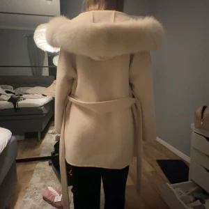 Beige kappa från FUR Stockholm - Fin vinterkappa från Fur Stockholm, köpte den förra vintern för 2199 kr. Denna ljusa, eleganta kappa med mysig pälskantad huva har endast blivit använd under en månads tid så den är i nyskick utan några som helst fel eller fläckar – praktiskt taget som ny! Perfekt för den kommande vintern, både stilren och varm. Jag säljer den endast för att det inte är min stil längre och då jag ej tycker att den passar mig😊
