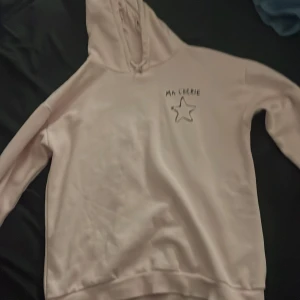 Ljusrosa hoodie från Gina Tricot - Säljer en ljusrosa hoodie från Gina Tricot med texten 'Ma Chérie' och en stjärna tryckt på framsidan. Den är i bra skick men har en liten fläck. Perfekt för en mysig dag hemma eller en avslappnad utflykt. 🩷