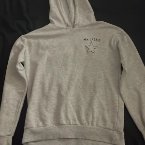 Grå hoodie från Gina Tricot - Mysig grå hoodie från Gina Tricot med texten 'Ma Chérie' och en stjärna broderad på bröstet. Perfekt för en avslappnad dag eller en kylig kväll. Den har en klassisk passform och är superbekväm. 🩶