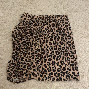 Leopard kjol - Snygg leopardmönstrad tight kjol med rynkade detaljer på sidan! Använd få gånger och i mycket bra skick!
