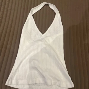 Vit ribbad halterneck topp från BikBok - Säljer en stilren vit halterneck topp från BikBok i storlek L. Toppen har en ribbad struktur och en djup v-ringning som ger en snygg look. Perfekt för varma dagar eller sommarens fester. Hör av dig vid intresse! Aldrig använd och säljer för 80 kronor.✨