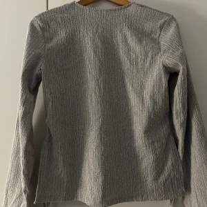 Grå tröja från Zara - Säljer en stilren grå tröja från Zara med långärmad design. Tröjan har en texturerad yta som ger den ett unikt utseende. Perfekt för en minimalistisk garderob.