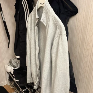 Grå stickad zip up kofta - Snygg och stilren grå kofta från Acne Studios. Den har en ribbad krage och långa ärmar, perfekt för lager-på-lager under kyligare dagar. Koftan är tillverkad i ett mjukt material som ger en bekväm passform. Pris kan diskuteras!