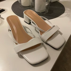 Klackar  - Stilrena vita klackar med fyrkantig tå och bred klack. De har en enkel remdesign som ger en modern look. Perfekta för balen😍 aldrig använt då de är lite små. Storlek 38❤️