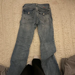 Blå jeans från hm - Säljer ett par klassiska blå jeans från hm. De har en straight passform och är tillverkade i denim. Jeansen har fem fickor och knappar bak. Perfekta för en avslappnad stil.