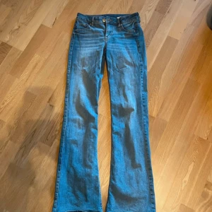 Blå bootcut jeans - Snygga blå bootcut jeans med låg midja. Perfekta för en avslappnad stil. Klassisk design med dragkedja och knapp framtill.