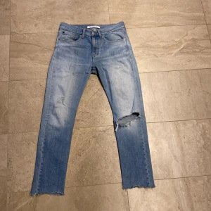 Ljusblå jeans från Calvin Klein - Feta ljusblå jeans från Calvin Klein i premium italiensk denim. De har en fransig nederkant och en cool reva på ena benet. Perfekta för en avslappnad stil. Storlek midja: 30 längd: 32. 8/10 skick, har bara använt dem några gånger🤙