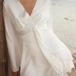 Vit adoore klänning  - Elegant vit klänning med långa vida ärmar och knytband i midjan. Perfekt som studentklänning. Helt oanvänd. Storlek 36🥰