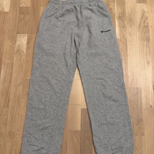 Grå mjukisbyxor från Champion - Säljer ett par grå mjukisbyxor från Champion. Byxorna har en elastisk midja och muddar vid bensluten för extra komfort. Perfekta för en avslappnad stil. 🩶 