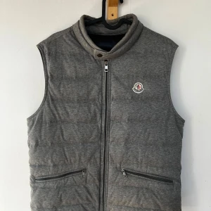 Moncler Gerard Väst - Grå Moncler Gerard väst Size 3 fits M/L Cond 7/10, två små flaws (vid dragkedjan och under höger arm, se bilder), dragkedjan är även lite seg men utöver det är den i bra skick  Äkta såklart!  Bara att höra av sig för fler bilder eller vid frågor!