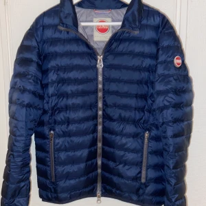 Blå pufferjacka från Colmar - Säljer en snygg blå pufferjacka från Colmar. Jackan har en quiltad design med dragkedja framtill och två praktiska fickor med dragkedja. Perfekt för kyligare dagar med sin stilrena look och bekväma passform.