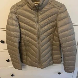 Beige pufferjacka från Corneliani - Säljer en snygg beige pufferjacka från Corneliani. Den är perfekt för kyliga dagar med sin quiltade design och dragkedja framtill. Jackan har en stilren look och är superbekväm att ha på sig. Passar perfekt till både vardag och lite finare tillfällen.