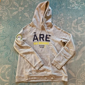 Åre hoodie - Grå hoodie med text fram. Bra skick. Snören vid luvan. 