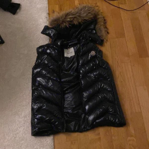 Moncler väst! - Säljer denna då den ej kommer till användning! Dragkedjan är trasig annars felfri! Luvan är borttagbar! Storlek XL men passar mer som S-M