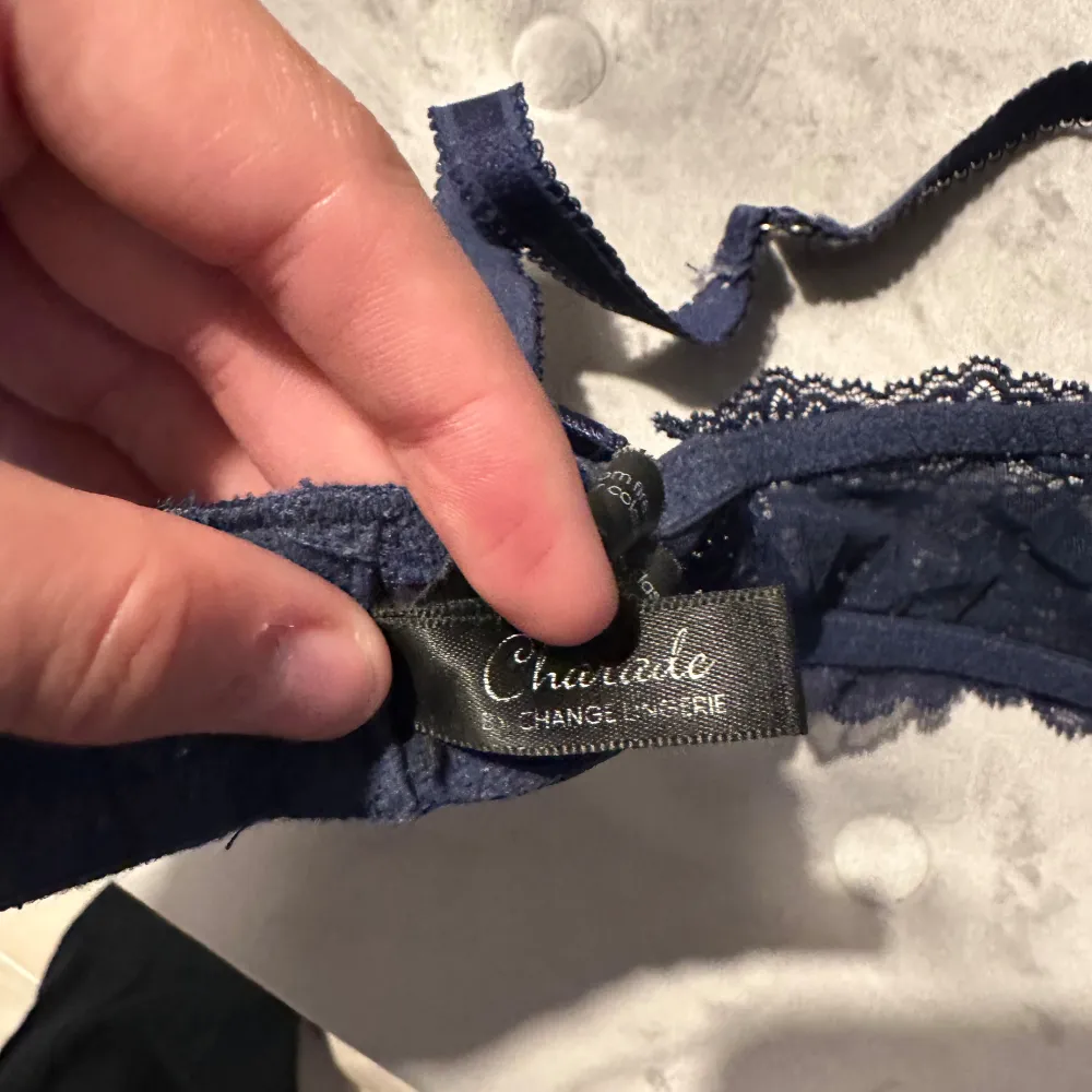 Säljer en elegant mörkblå bh från Change Lingerie. Den har vacker spetsdetaljering och en liten rosett med hängande smycke mellan kuporna. Perfekt för en lyxig känsla under kläderna. Nypris är 879kr.. Toppar.