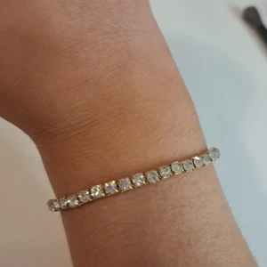 Glittrigt armband med stenar - Säljer ett superglittrigt armband med klara stenar som verkligen fångar ljuset. Perfekt för att lägga till lite extra bling till din outfit. Armbandet är elegant och passar både till vardags och fest. Ett måste för alla som älskar att glittra!
