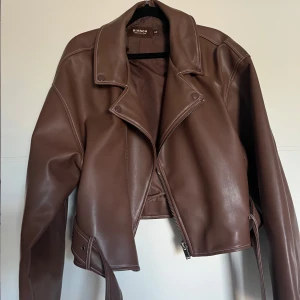 Brun skinnjacka - Säljer en brun skinnjacka från Nelly. Lite större i storlek och i en boxig, kort modell. I mycket bra skick, bara använd fåtal gånger.