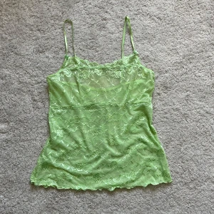 Grönt mesh linne - Säljer en så söt topp i ett blommigt mesh/spets material! Så skönt och stretchigt. Har ett svart linne under på sista bilden🫶