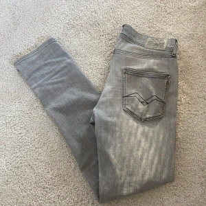 Grå jeans från Replay - Säljer ett par snygga grå jeans från Replay. Säljer de pga de inte kommer till användning. Killen på bilden är 173.Det finns ett litet hål (se bild 4) men syns inte vid användning! Hör av er om ni har frågor!