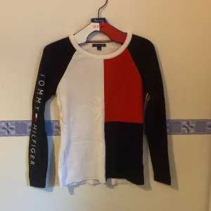 Flerfärgad långärmad tröja från Tommy Hilfiger - Säljer en supercool långärmad tröja från Tommy Hilfiger. Den har ett blockmönster i vitt, rött och blått, med Tommy Hilfiger-loggan tryckt längs ena ärmen. Tröjan är i ett ribbat material som ger en skön passform. Perfekt för höst och vår! Strl s/m