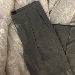 Grå kostymbyxor i storlek S - Gråa supersnygga kostymbyxor från Ginatricot, formgivande, använda fåtal gånger. Hör av dig vid frågor, köparen står för frakt☺️💗