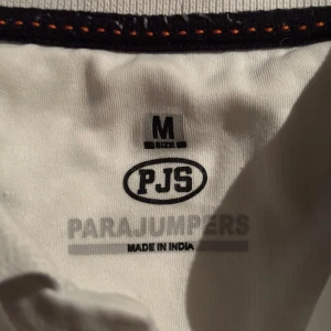 Vit pikétröja från Parajumpers🍾 - Säljer en stilren vit pikétröja från Parajumpers med klassisk krage och knappdetaljer. Tröjan har en broderad logotyp på bröstet som ger en exklusiv touch. Perfekt för en avslappnad men ändå snygg look. Ny pris 1699kr ingen marken nesten ny