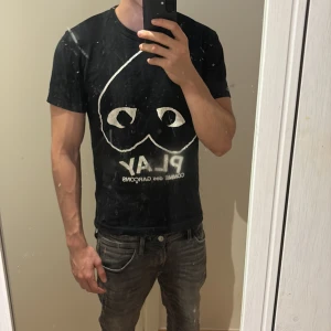 Svart t-shirt från Comme des Garçons - Säljer en svart t-shirt från Comme des Garçons med det ikoniska hjärtmotivet och texten 'PLAY' på framsidan. T-shirten är kortärmad och har en normal passform. Perfekt för en stilren och trendig look. Lite sprickning i trycket men syns bara på nära håll.