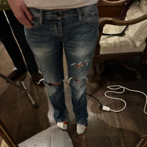 slitna tommy hilfiger jeans - Säljer ett par blå jeans med slitningar på knäna. De är från Tommy Hilfiger men köpta second hand och slitningarna är gjorda själv. Jag bär normalt sätt 38 men passar även 36 och 40 beroende på hur man vill att de ska sitta. Jag är 175 cm lång. 