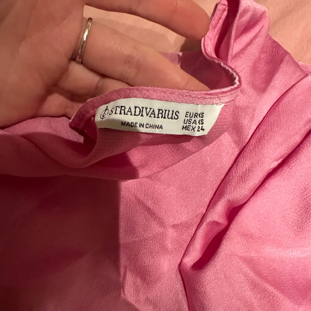 Säljer en söt rosa klänning från Stradivarius med korta ärmar och v-ringad design. Perfekt för sommarens varma dagar. Klänningen har en omlott-look som ger en fin passform.. Mekot.