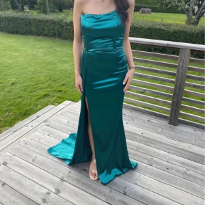 Grön axelbandslös långklänning - Elegant grön axelbandslös långklänning i satin med en slits framtill men även med ett släp.