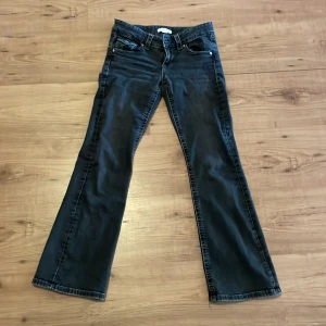 Svarta bootcut jeans från Gina Tricot - Snygga svarta lågmidjade bootcut jeans från Gina Tricot. De har knappar bak. 