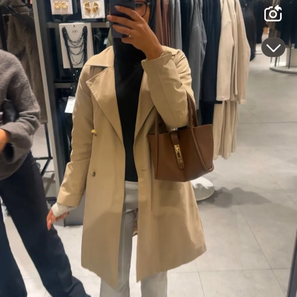 Snygg beige trenchcoat med klassisk design och knappar framtill. Perfekt för övergångsperioder och ger en stilren look. Passar bra till både vardag och mer uppklädda tillfällen.. Takit.