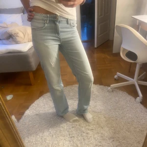 Ljusblå jeans - Snygga ljusblå jeans med en klassisk straight passform. De är midwaist och är perfekta för en avslappnad stil. Jeansen har en enkel design med fem fickor och knappgylf. De har också en snygg detalj på låret