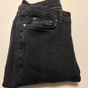 Svarta jeansbyxor - Snygga svarta jeansbyxor med en tight passform. De har klassiska fem fickor och en knappgylf. Perfekta för en stilren look.