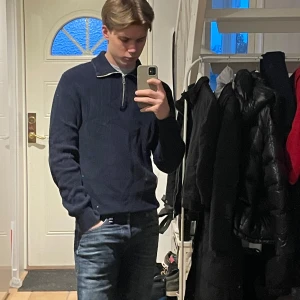 Mörkblå stickad tröja med dragkedja - Säljer en stilren mörkblå stickad tröja med dragkedja vid halsen. Tröjan har långa ärmar och en klassisk passform, perfekt för kyligare dagar. Köptes på brothers !