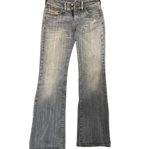 Blå bootcut jeans - Snygga blå bootcut jeans med en klassisk tvätt och femficksdesign. Perfekta för en avslappnad stil. De har en knapp- och dragkedjestängning framtill. Jeans är jätte bra skick och är från diesel , säljer för den var tyvärr för små för mig 
