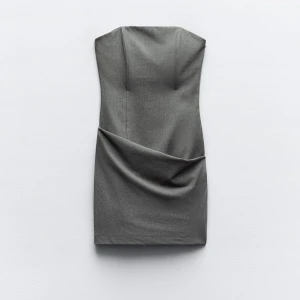 Grå axelbandslös klänning - Elegant grå axelbandslös klänning med draperad detalj framtill. Perfekt för en stilren look.