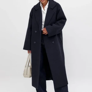 Mörkblå Na-kd kappa - Mörkblå kappa med knappar och bälte i midjan. Långärmad design med klassisk krage, perfekt för kyligare dagar. Stilren och tidlös, passar till många olika outfits. Helt slutsåld och i nyskick! Säljer då jag fick den i julklapp men redan har en liknande! ❣️❣️(na-kd premiumkvalitet) 