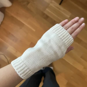 Vita stickade handledsvärmare - Säljer ett par vita stickade handledsvärmare som är perfekta för att hålla händerna varma. De har en ribbstickad kant och är utan fingrar, vilket ger bra rörelsefrihet. Perfekt för kyliga dagar!