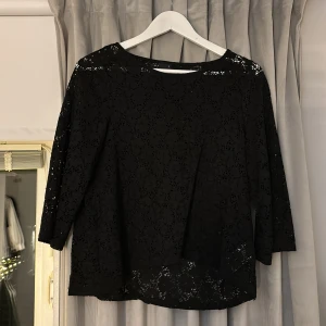 Svart spetsblus från Gina Tricot - Snygg svart spetsblus från Gina Tricot med trekvartsärm. Perfekt för en elegant look med sitt genombrutna mönster. Passar bra till både jeans och kjol.